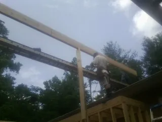 Carpenter setting a ridge beam over a new addition frame — Ice Dam Removal by Roofing Brothers in Scotts