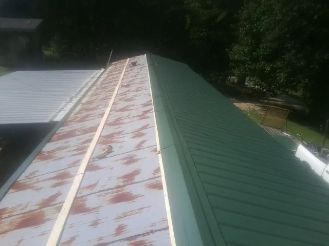 Old rusted panels beside newly installed green metal roofing — Wind Damage Roof Repair by Roofing Brothers in Scotts