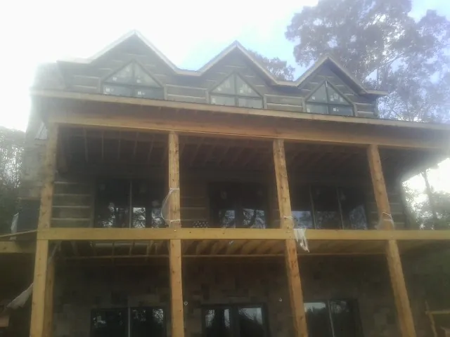 Dormers and porch framing on a large log home under construction — Roof Coating work by our crew in Scotts
