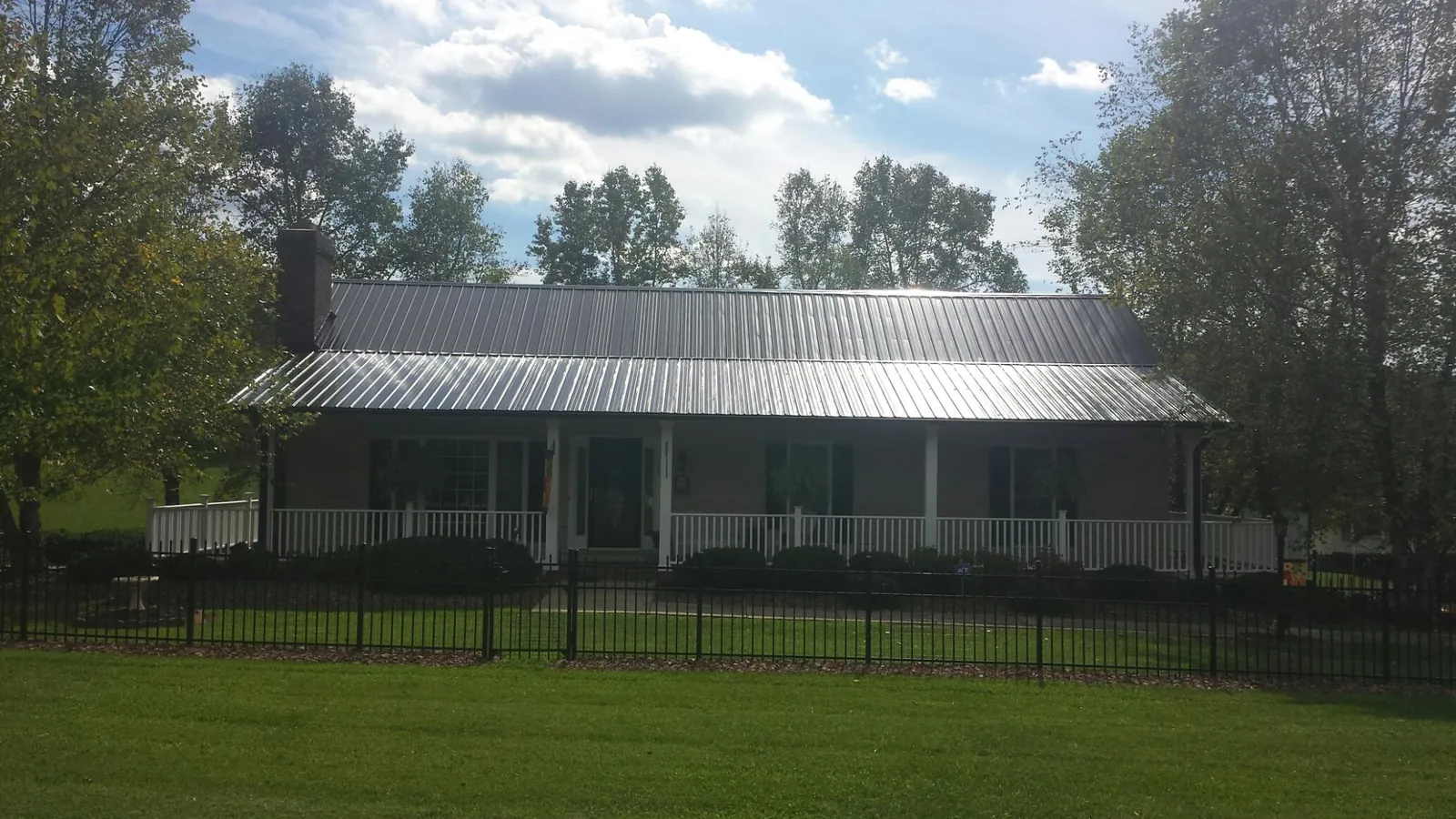 Gray metal roof on a brick ranch with a full width front porch — Gutter Guard Installation work by our crew in Scotts