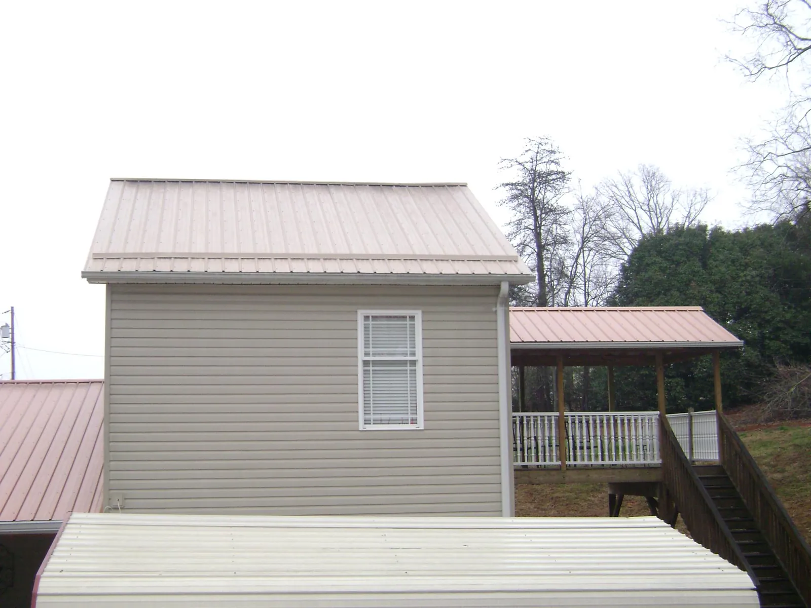 Tan metal roofs on a two story addition and attached porch, from a Roof Replacement job in Scotts