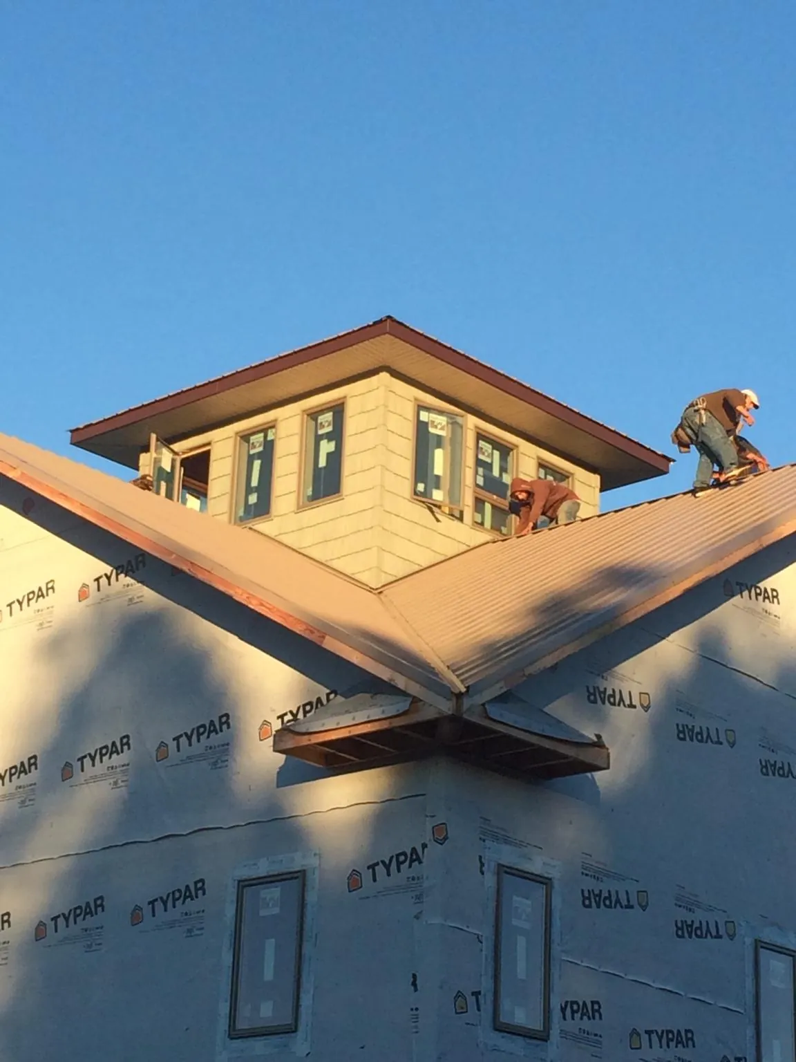 Roofers working around a rooftop cupola on a new metal roof at sunset — Roof Waterproofing in Scotts by Roofing Brothers